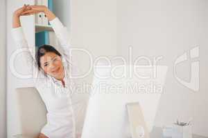 Casual businesswoman stretching at her desk