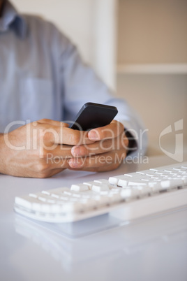 Businessman texting on phone at desk