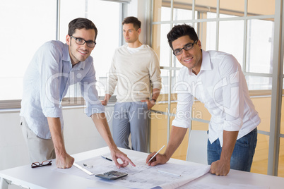 Casual architecture team working together at desk smiling at cam