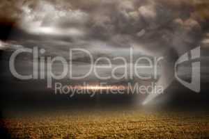 Stormy sky with tornado over field