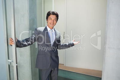Confident estate agent standing at front door welcoming you in