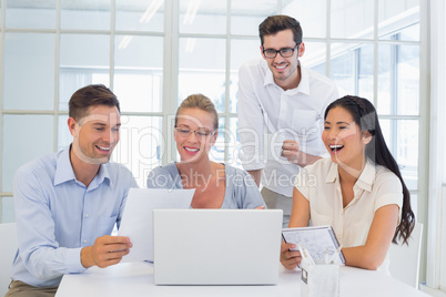 Casual business team laughing together at desk