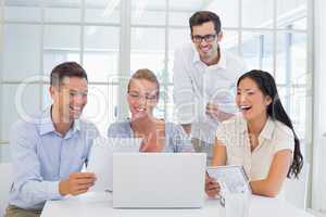 Casual business team laughing together at desk