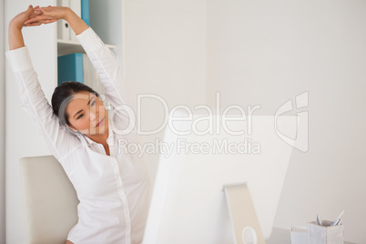 Casual businesswoman stretching at her desk