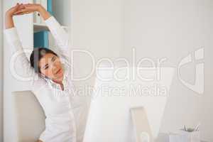 Casual businesswoman stretching at her desk