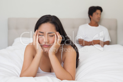 Woman lying on bed with boyfriend sitting