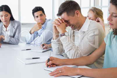 Casual businessman trying not to laugh during meeting