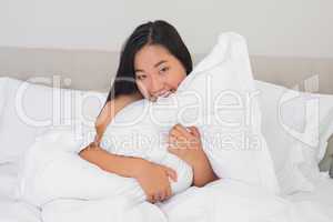 Smiling woman hugging her pillow