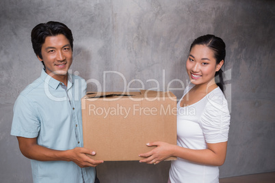 Happy couple holding a cardboard moving box