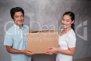 Happy couple holding a cardboard moving box