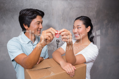 Happy couple holding house key and leaning on moving box