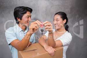 Happy couple holding house key and leaning on moving box