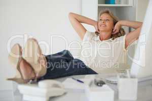 Casual businesswoman sitting at her desk with feet up