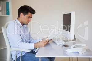 Casual businessman reading document at his desk