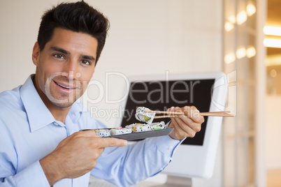 Casual businessman enjoying sushi at his desk