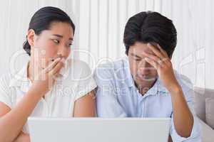 Worried couple using laptop together