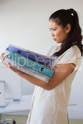 Casual businesswoman carrying pile of folders