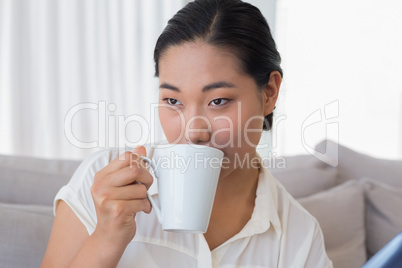 Smiling woman sitting on couch having coffee