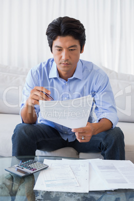 Man sitting on couch working out his finances