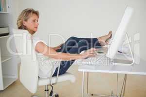 Casual businesswoman working with her feet up at desk