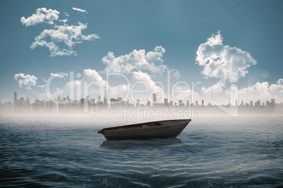 Small boat in the sea with city on horizon