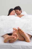 Couples feet sticking out from under duvet