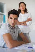 Casual business team looking at camera together at desk