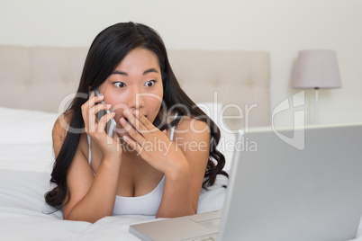 Shocked woman looking at laptop on the phone