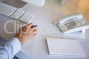 Casual businessman at desk with notepad and telephone