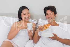 Happy couple having breakfast in bed