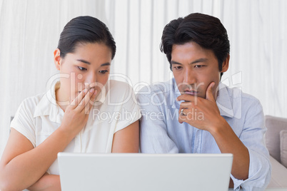 Worried couple using laptop together