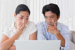 Worried couple using laptop together