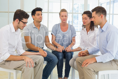 Group therapy in session sitting in a circle holding hands