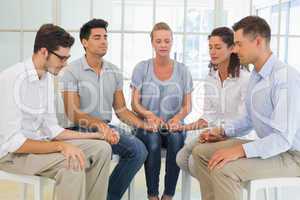 Group therapy in session sitting in a circle holding hands