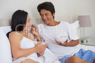 Happy couple having breakfast in bed