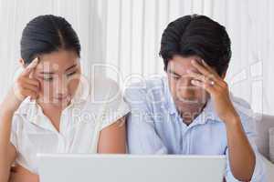 Worried couple using laptop together