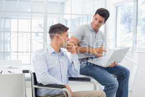 Casual businessman in wheelchair talking with colleague