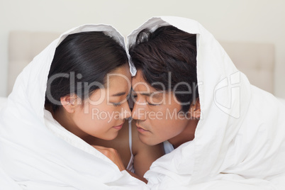 Happy couple lying on bed together under the duvet