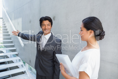 Estate agent showing stairs to customer and smiling