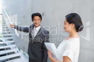 Estate agent showing stairs to customer and smiling