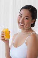 Pretty asian woman holding glass of orange juice