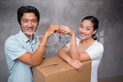 Happy couple holding house key and leaning on moving box