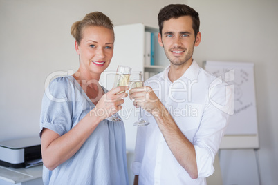 Casual business team smiling at camera toasting with champagne