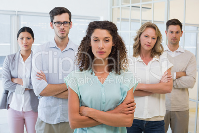 Casual business team frowning at camera with arms crossed