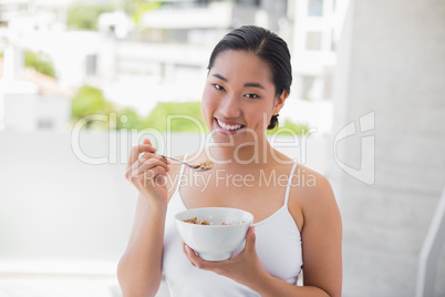Happy woman eating bowl of cereal
