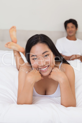 Woman lying on bed smiling at camera