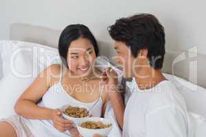 Happy couple having breakfast in bed