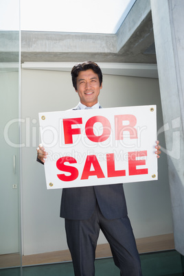 Confident estate agent standing at front door showing for sale s