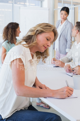 Casual businesswoman taking notes during meeting