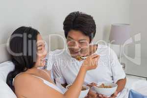 Happy couple having breakfast in bed